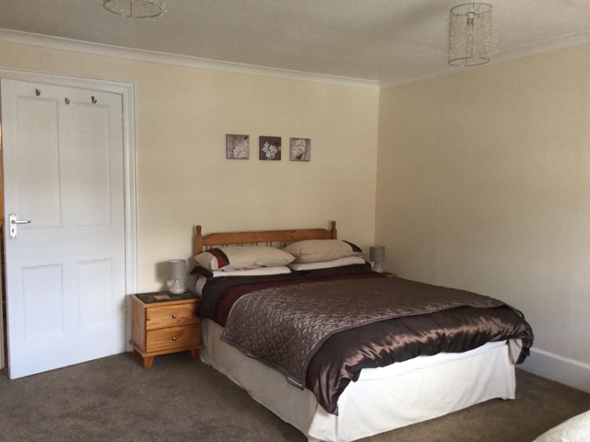 A bedroom with a bed, a nightstand, a dresser, and a door.