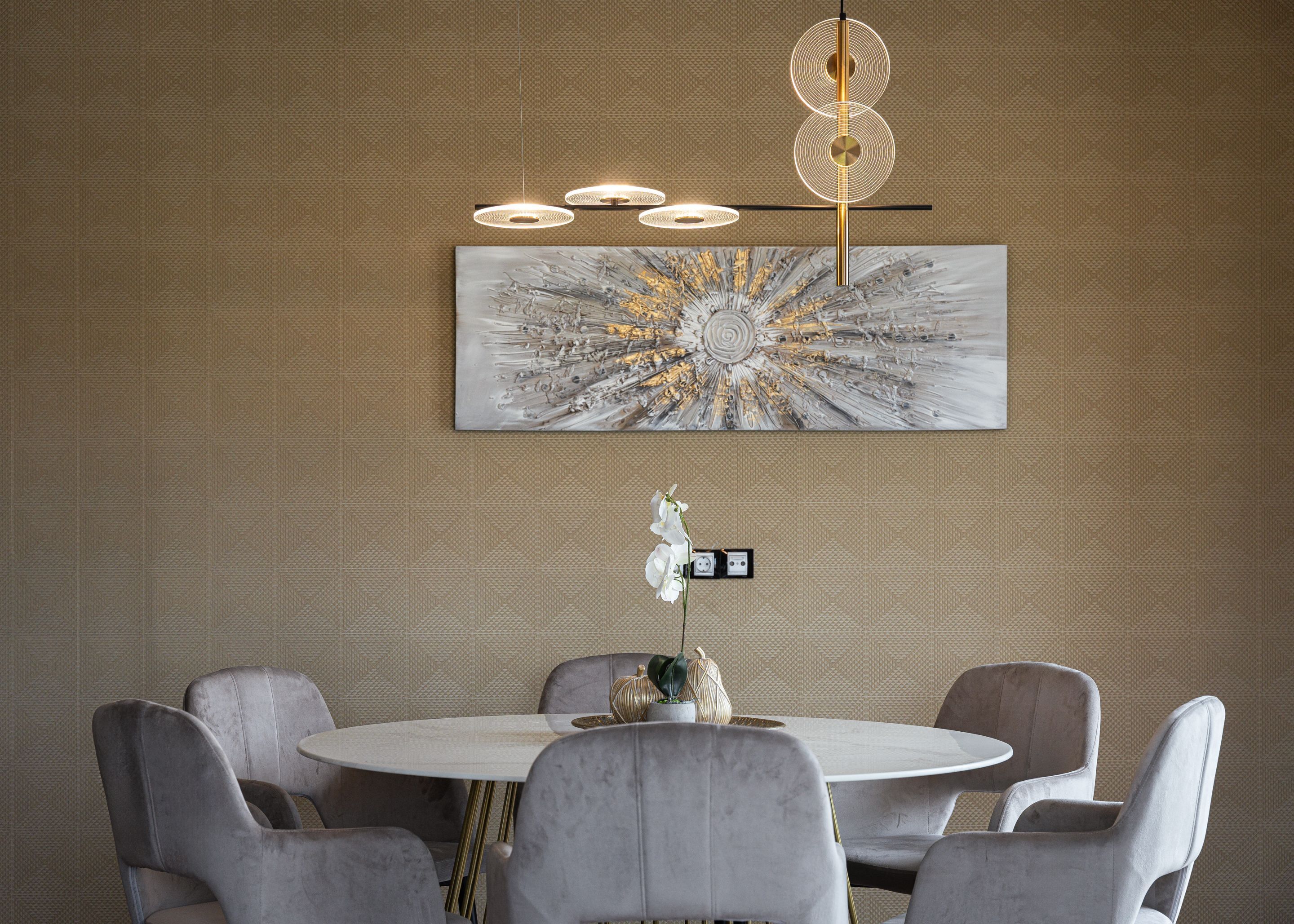 A modern dining area with a round table and six chairs, a large abstract painting on the wall, and a unique pendant light fixture.