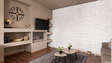 Una sala de estar moderna con una pared de piedra, un reloj de pared, un televisor de pantalla plana y una pequeña mesa redonda con dos plantas en macetas.
