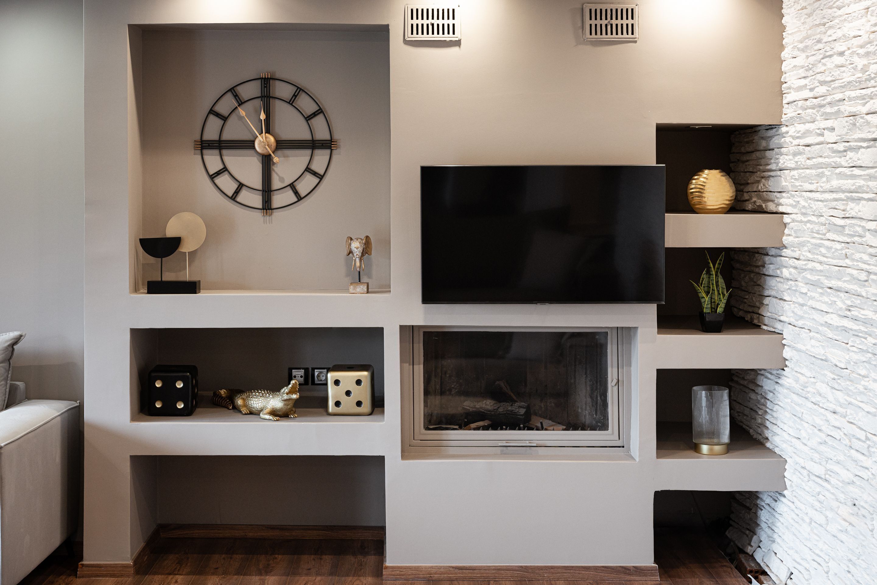 A modern living room with a mounted TV, a fireplace, and decorative items on shelves.