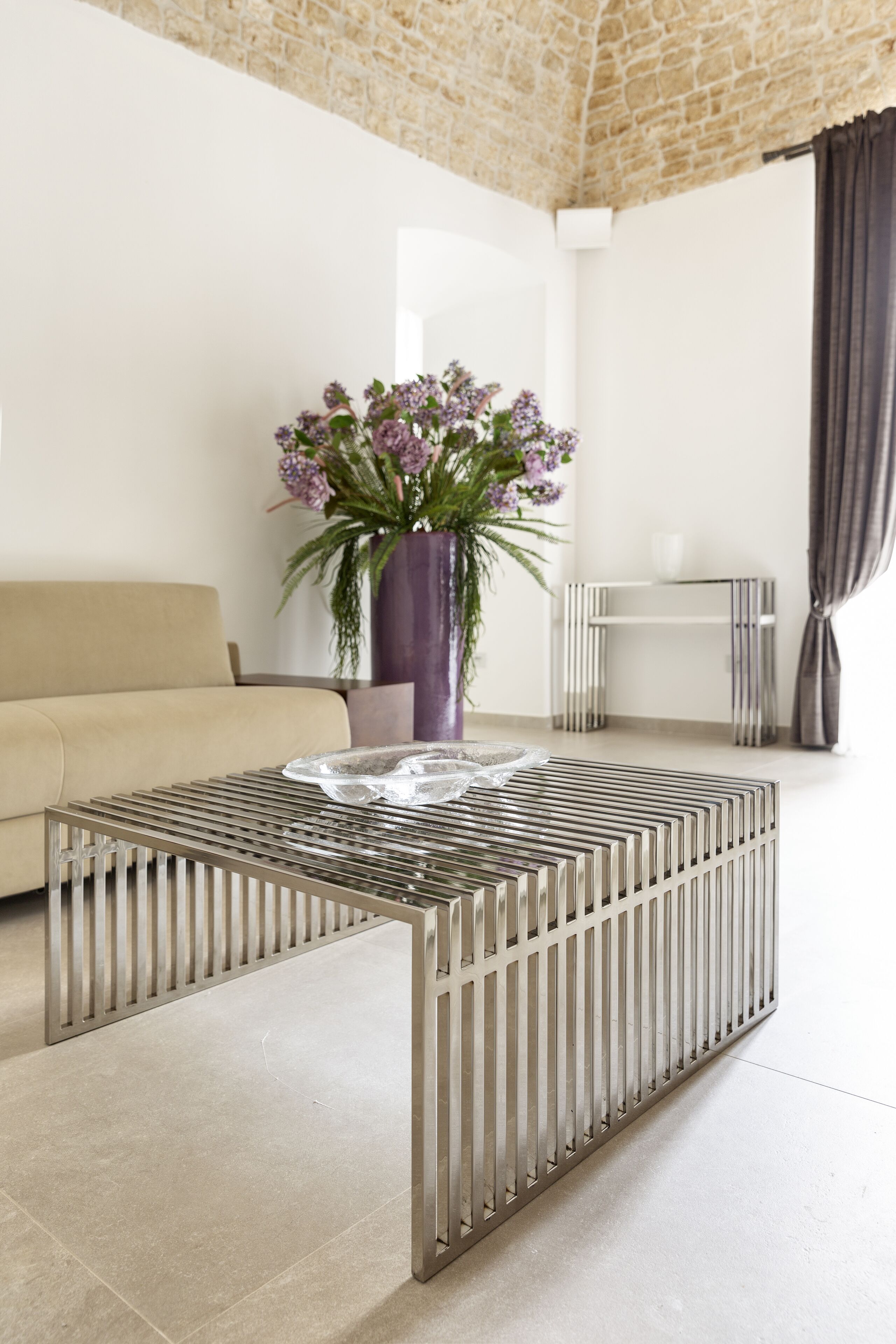 A modern living room with a sofa, a coffee table, a potted plant, and a striped side table.