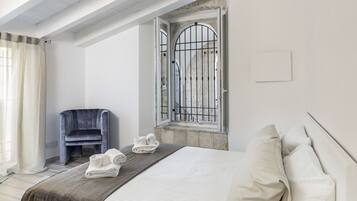 Een moderne slaapkamer met een gebogen bed, een stoel en een raam met metalen tralies.