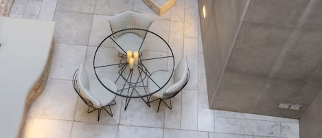 Eine Dachterrasse mit Steinmauer, Spüle und zwei Sitzbereichen mit runden Tischen und Stühlen.