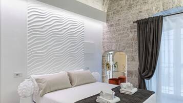 Ein modernes Schlafzimmer mit einem gewölbten Bett, einer strukturierten Wand und einer Steinwand dahinter.