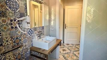 Un baño con lavabo, espejo y azulejos estampados.