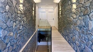 A hallway with stone walls and a glass railing, leading to a door at the end. - Tea Luxury (Praia a Mare)