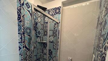 Un baño con ducha de mampara de vidrio, inodoro y lavamanos.