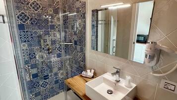 Un baño con ducha, lavamanos y espejo.