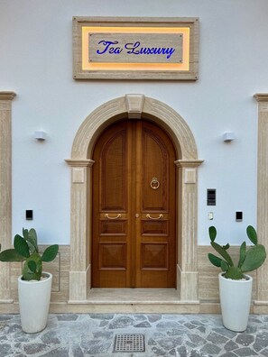 Una puerta doble de madera con un letrero encima que dice "Tea Luxury".