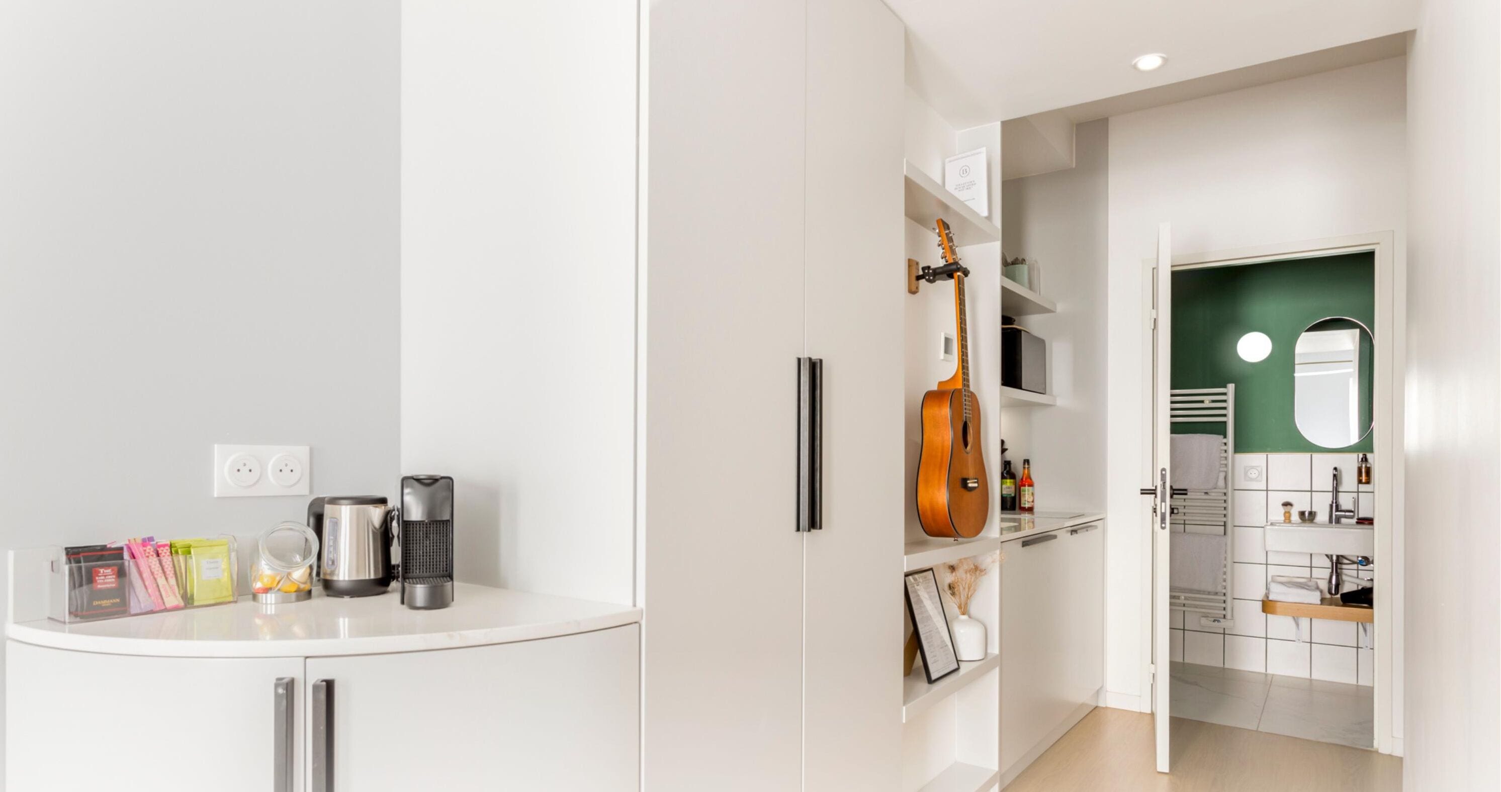 Une cuisine moderne avec des armoires blanches, une guitare intégrée et un mur d’accent vert.