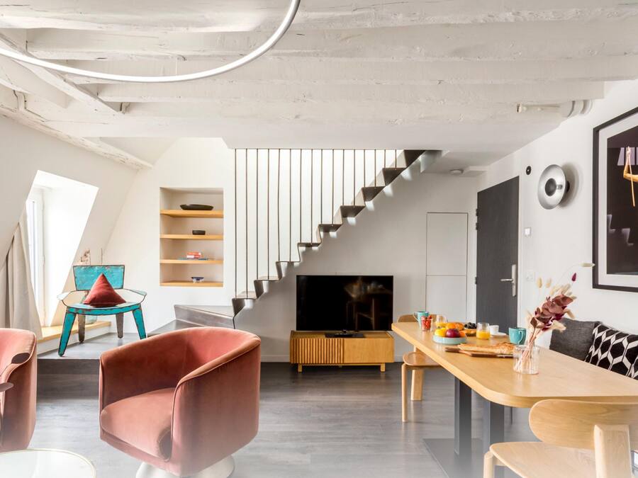 A modern living room with a staircase, a dining area, and a TV.