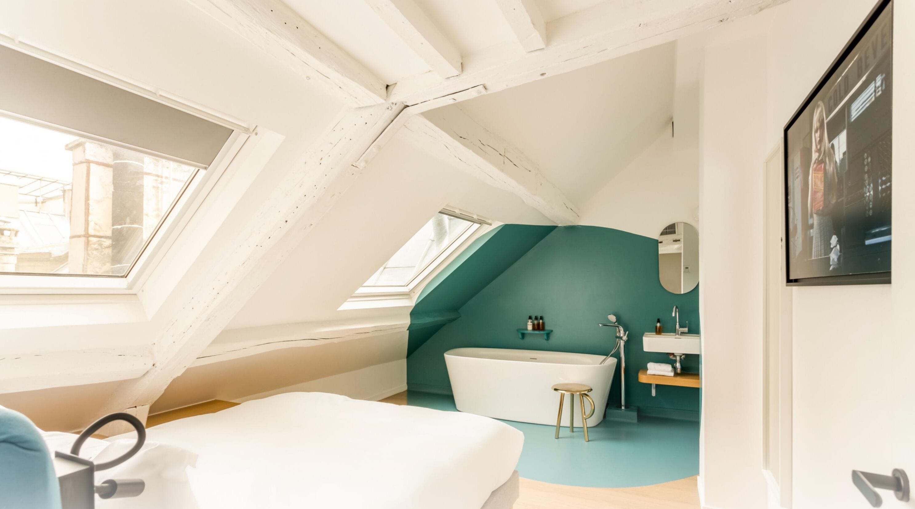 Une salle de bain moderne et compacte, dotée d’une baignoire sur pieds, d’un petit tabouret et d’un meuble-lavabo avec un miroir.