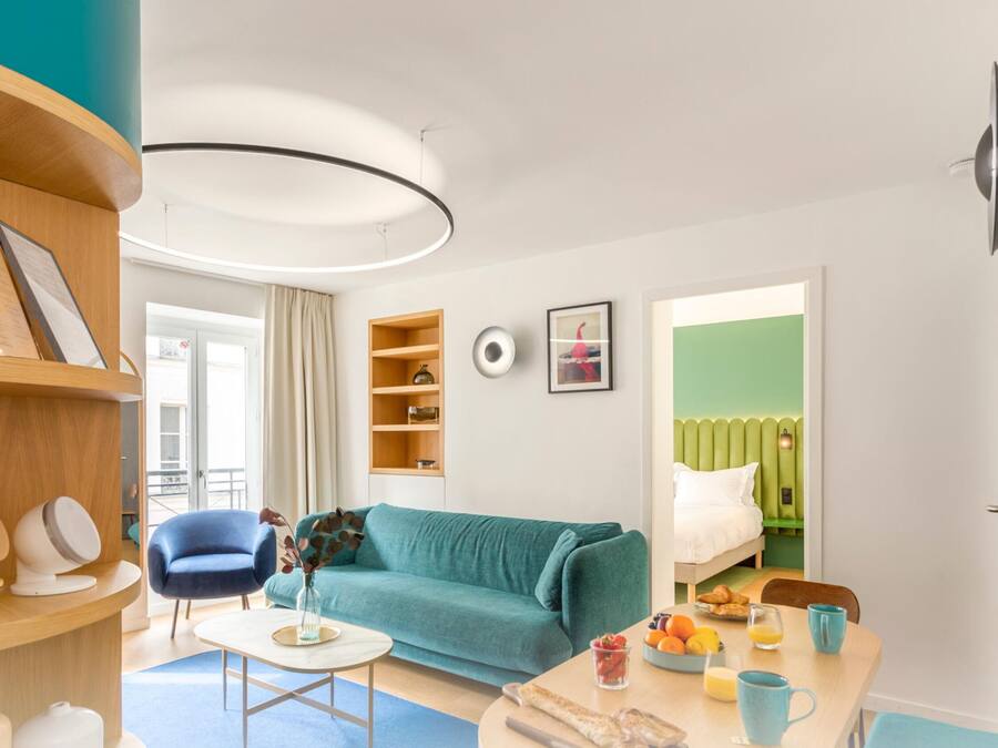 Una sala de estar moderna con un sofá color turquesa, una mesa de centro y una estantería.