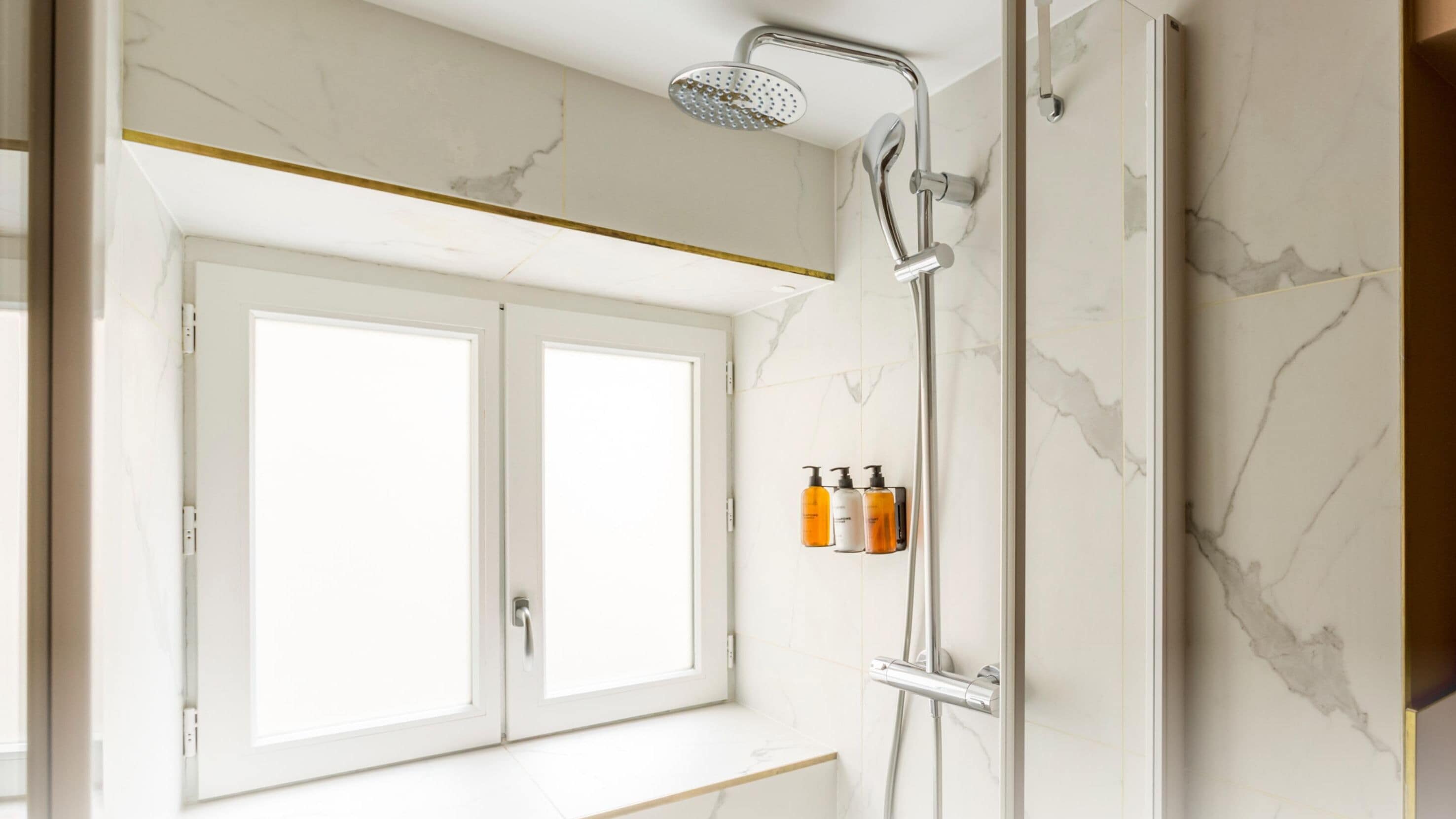 A modern bathroom with a shower, two sinks, and a window.