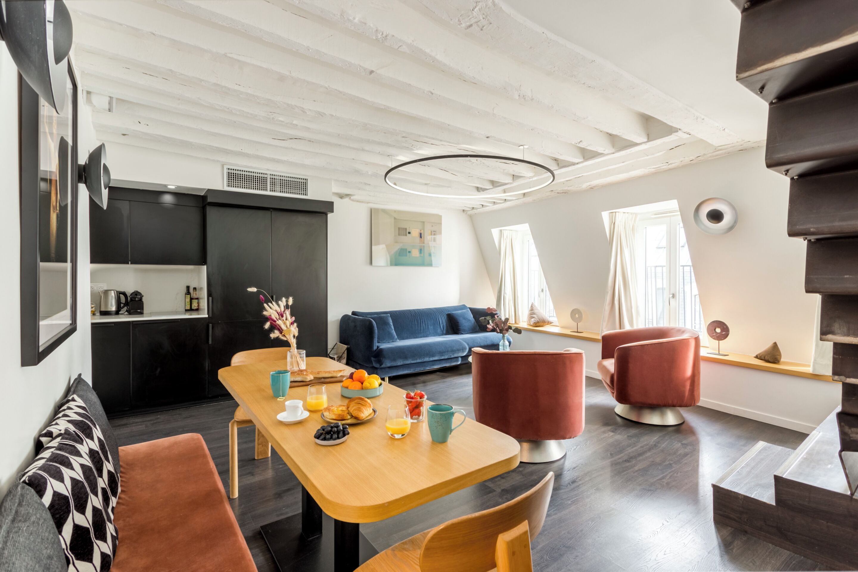 Ein moderner Wohnraum mit Essbereich, einer Couch und einer Treppe.