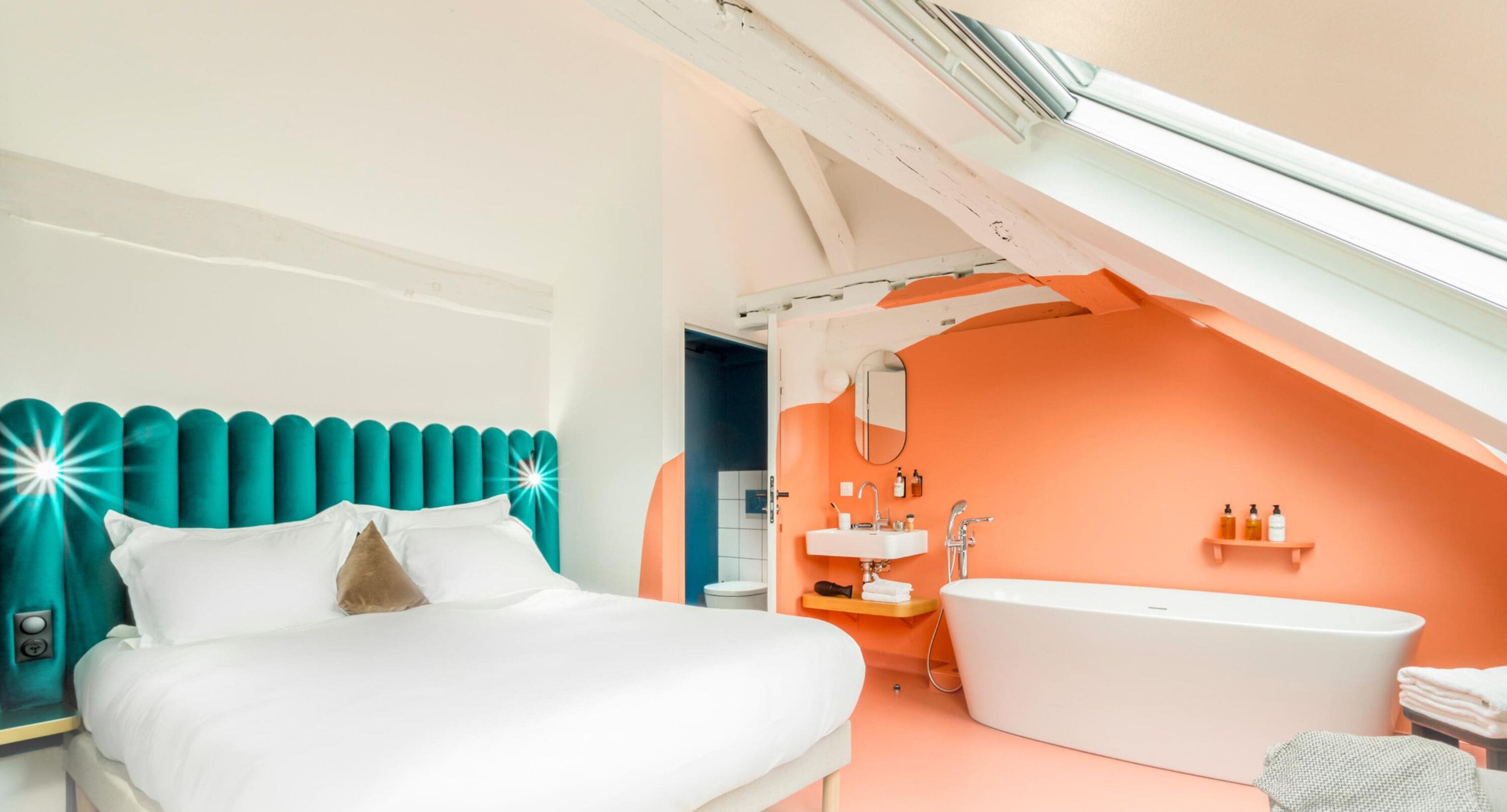 Un dormitorio moderno con una cama grande, un baño con bañera y un techo inclinado.