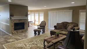 A living room with a fireplace, a sofa, a coffee table, and a lamp. - Spacious Split-Unit Home in Nassau Bay, Texas (Houston)