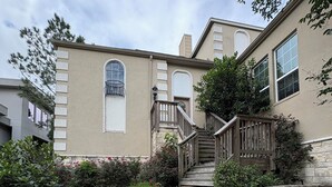 A stone staircase leading to a beige building with a number plaque reading "18654". - Spacious Split-Unit Home in Nassau Bay, Texas (Houston)