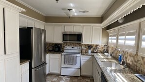 A kitchen with white cabinets, stainless steel appliances, a granite countertop, and a patterned backsplash. - Spacious Split-Unit Home in Nassau Bay, Texas (Houston)