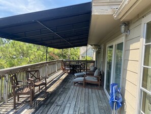 A covered outdoor deck with wooden furniture and a pergola.