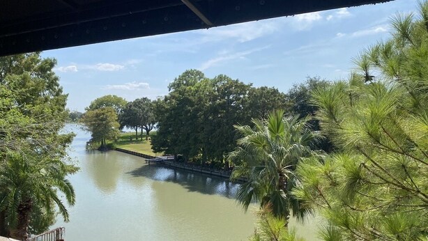 A view from under a bridge overlooking a calm river with trees and a wooden walkway. - Spacious Split-Unit Home in Nassau Bay, Texas (Houston)