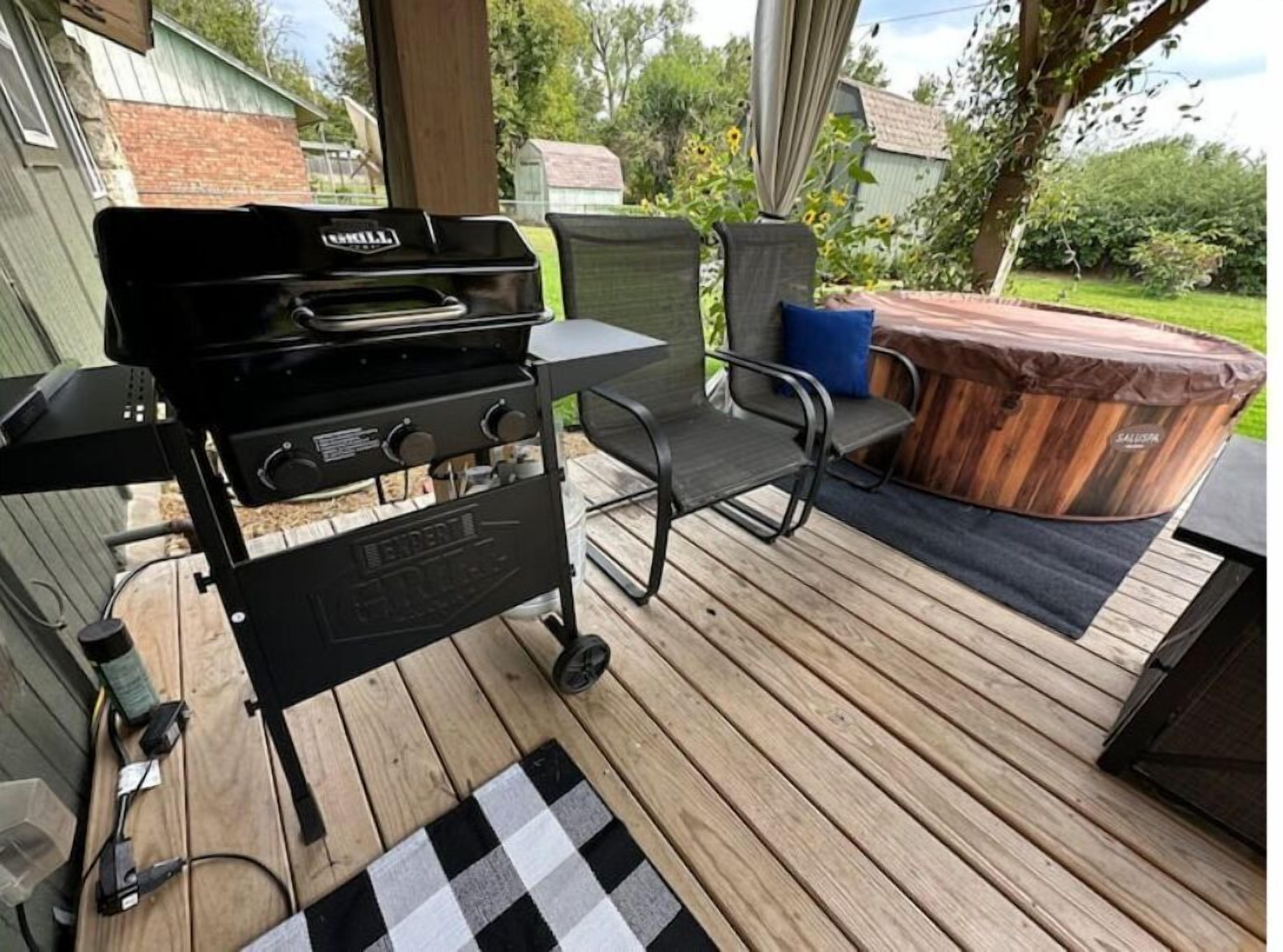 Un barbecue, une chaise et un jacuzzi sur une terrasse en bois.