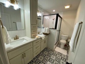 A bathroom with a white sink, mirror, and toilet. There is a patterned floor and a towel rack. - "The Big Cozy"- WiFi, Hot tub, Grill, Sleeps 8 (Tulsa)