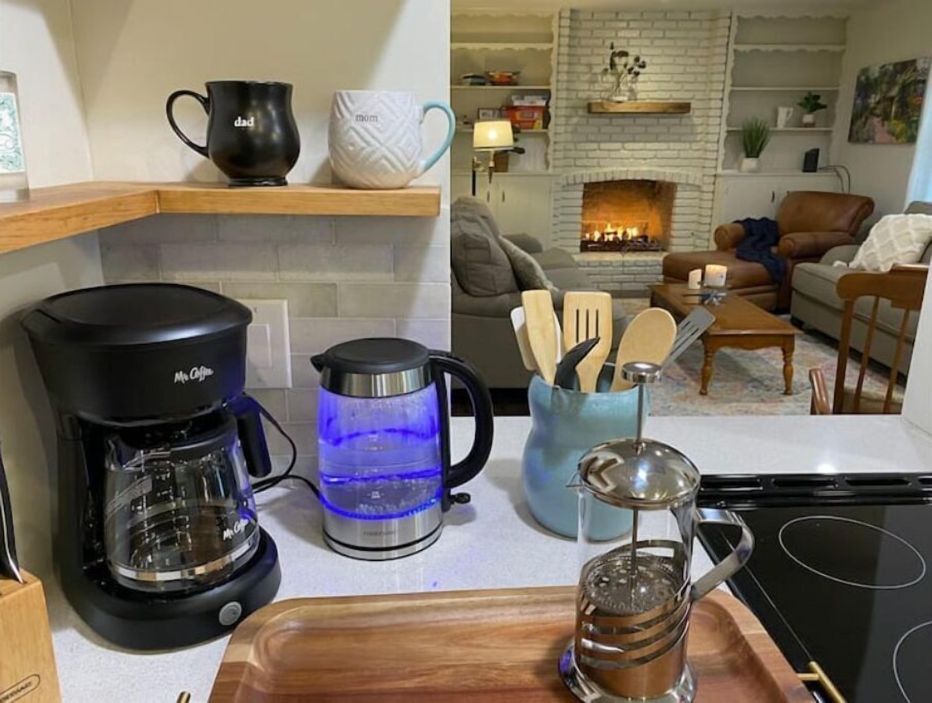 A kitchen with a coffee maker, a kettle, and a coffee pot on the counter.