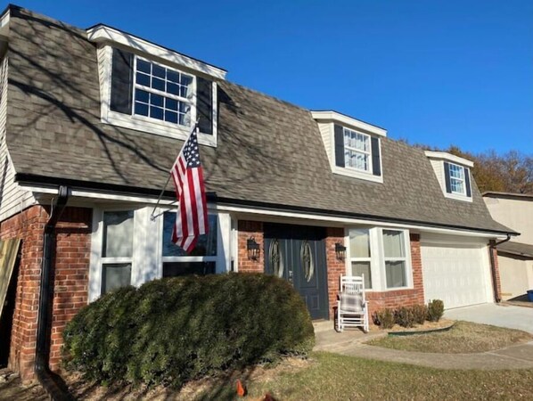 A two-story house with a brick facade, a front porch, and a garage. - "The Big Cozy"- WiFi, Hot tub, Grill, Sleeps 8 (Tulsa)