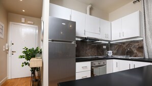 A modern kitchen with white cabinets, a stainless steel refrigerator, and a black countertop.