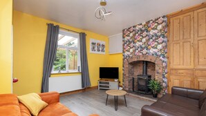 A living room with a fireplace, yellow walls, and a large window with curtains. - 3 Bed 1.5 Bath | Canal Side Location | Close To Wakefield & Leeds | Pets Welcome (Stanley)