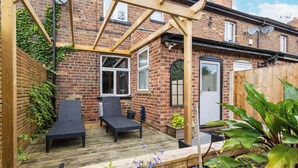 A patio with two black lounge chairs, a wooden pergola, and a brick house with a white door. - 3 Bed 1.5 Bath | Canal Side Location | Close To Wakefield & Leeds | Pets Welcome (Stanley)