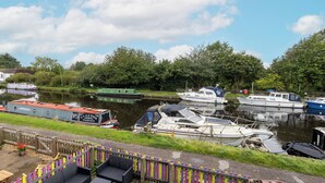 A riverside dock with various boats, a wooden fence, and outdoor seating. - 3 Bed 1.5 Bath | Canal Side Location | Close To Wakefield & Leeds | Pets Welcome (Stanley)