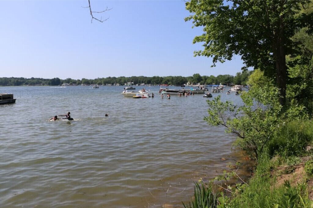A lake with boats and people swimming.