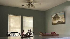 A kitchen with a gas stove, two windows with blinds, a ceiling fan, and a painting on the wall. - Indian Lake Cottage for Nature Lovers - Apt A

 (Dowagiac)