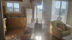 Ett modernt kök med kylskåp, ett matbord med stolar och en soffa.