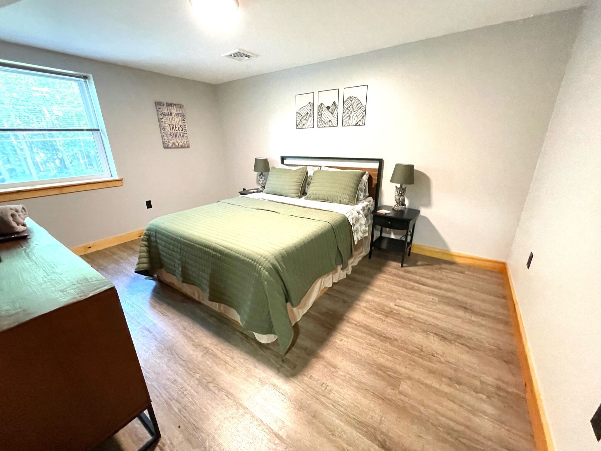 Une chambre à coucher avec un lit, des tables de chevet, un bureau et une fenêtre.