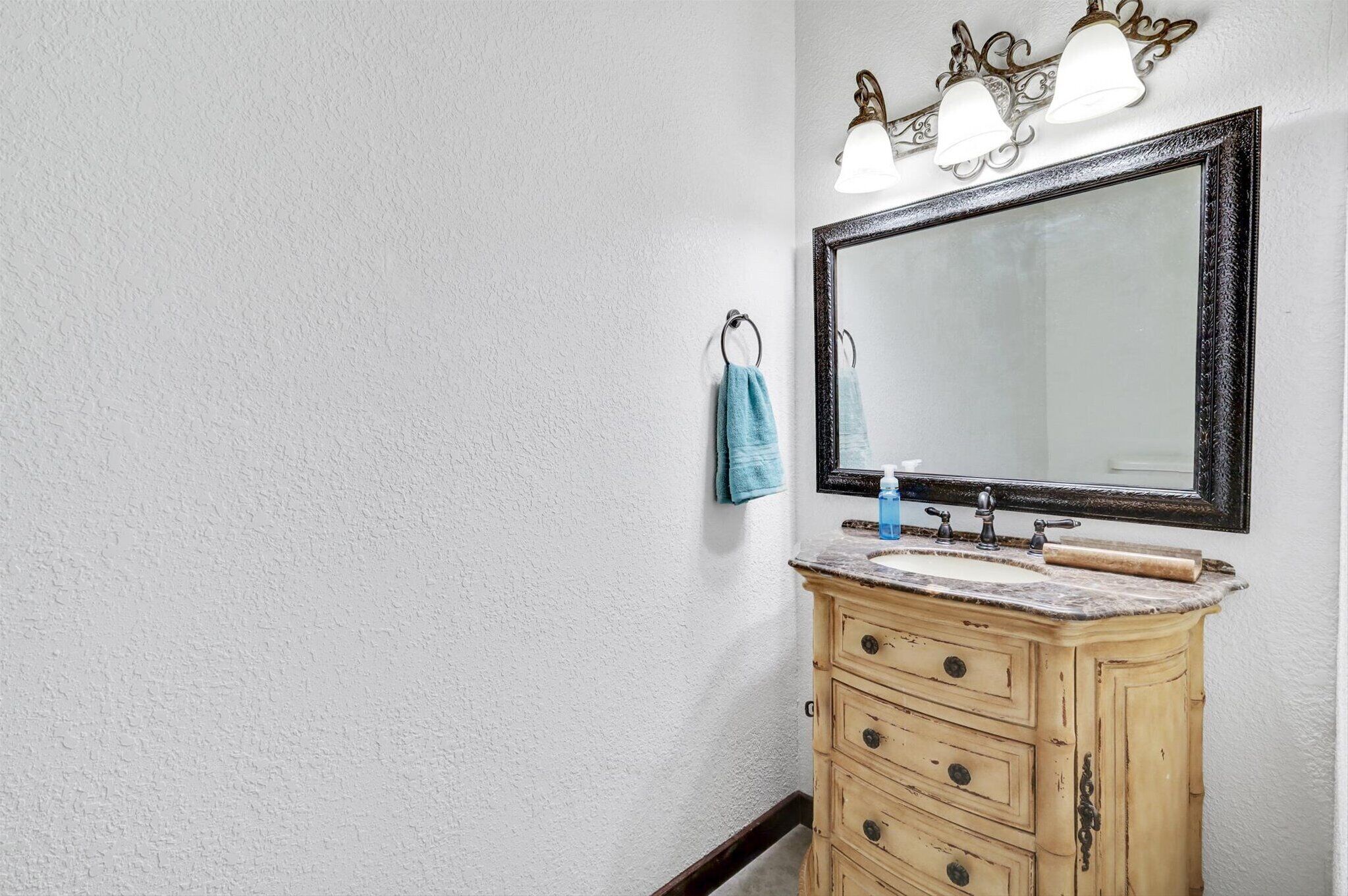 Une salle de bain avec un grand miroir, un meuble-lavabo en bois et deux luminaires placés au-dessus du miroir.