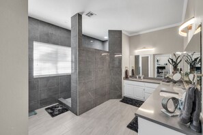 A modern bathroom with dark marble walls, a light wood floor, a large mirror, and a vanity with a towel rack. - The Tulsacation on Oxford (Tulsa)