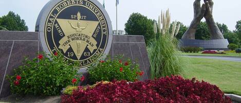 A university seal with a sculpture of hands above it.