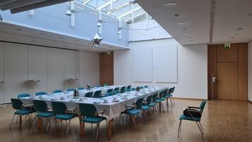 A conference room with a long table, teal chairs, and a high ceiling with skylights.