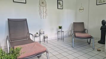 A waiting area with two chairs, a dreamcatcher, framed artwork, and a small table with a plant.