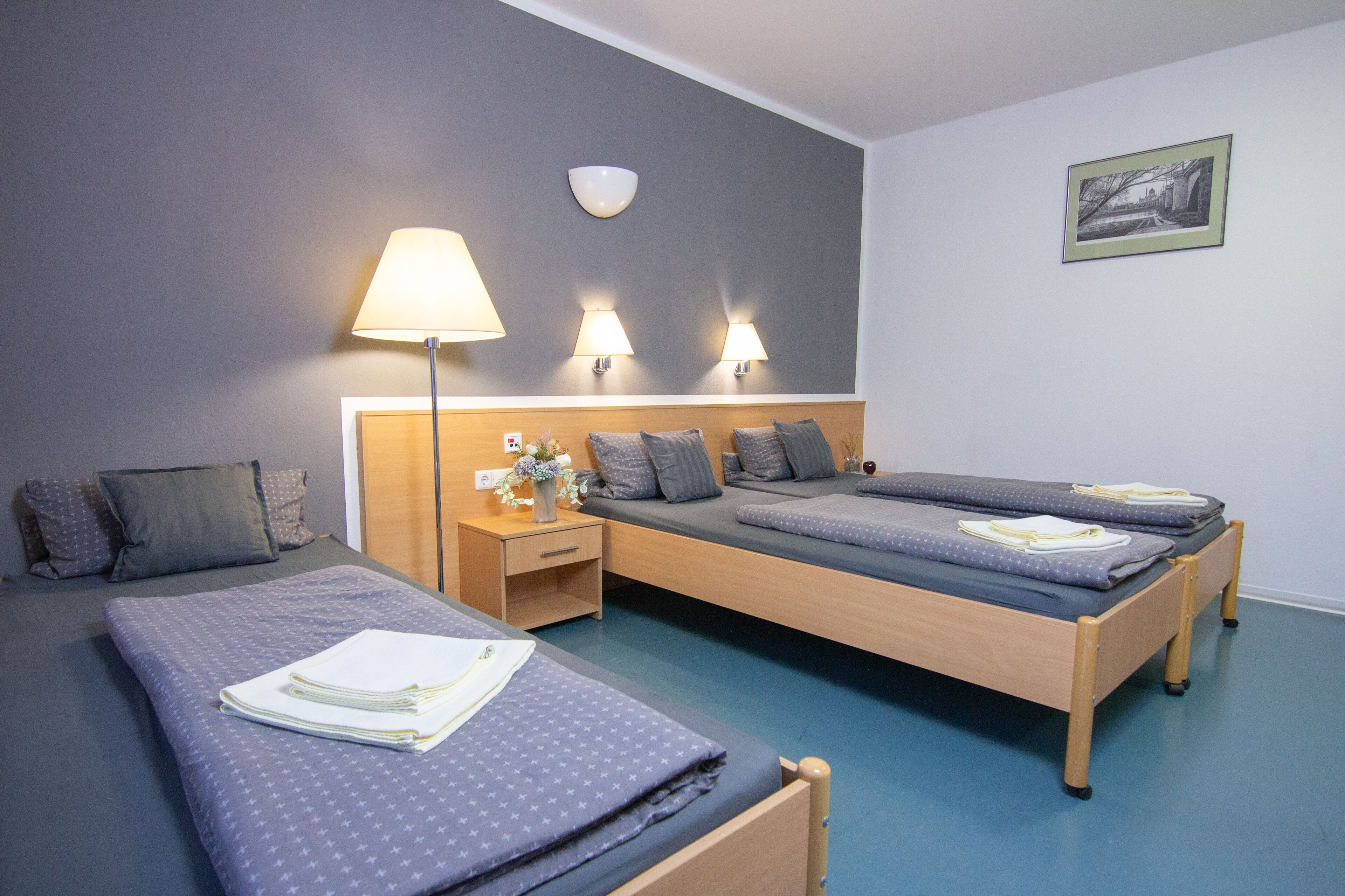 Ein Hotelzimmer mit zwei Betten, einem Nachttisch, einer Lampe und einer Wandleuchte.