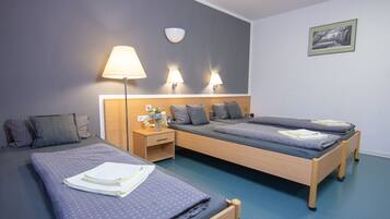 Ein Hotelzimmer mit zwei Betten, einem Nachttisch, einer Lampe und einer Wandleuchte.