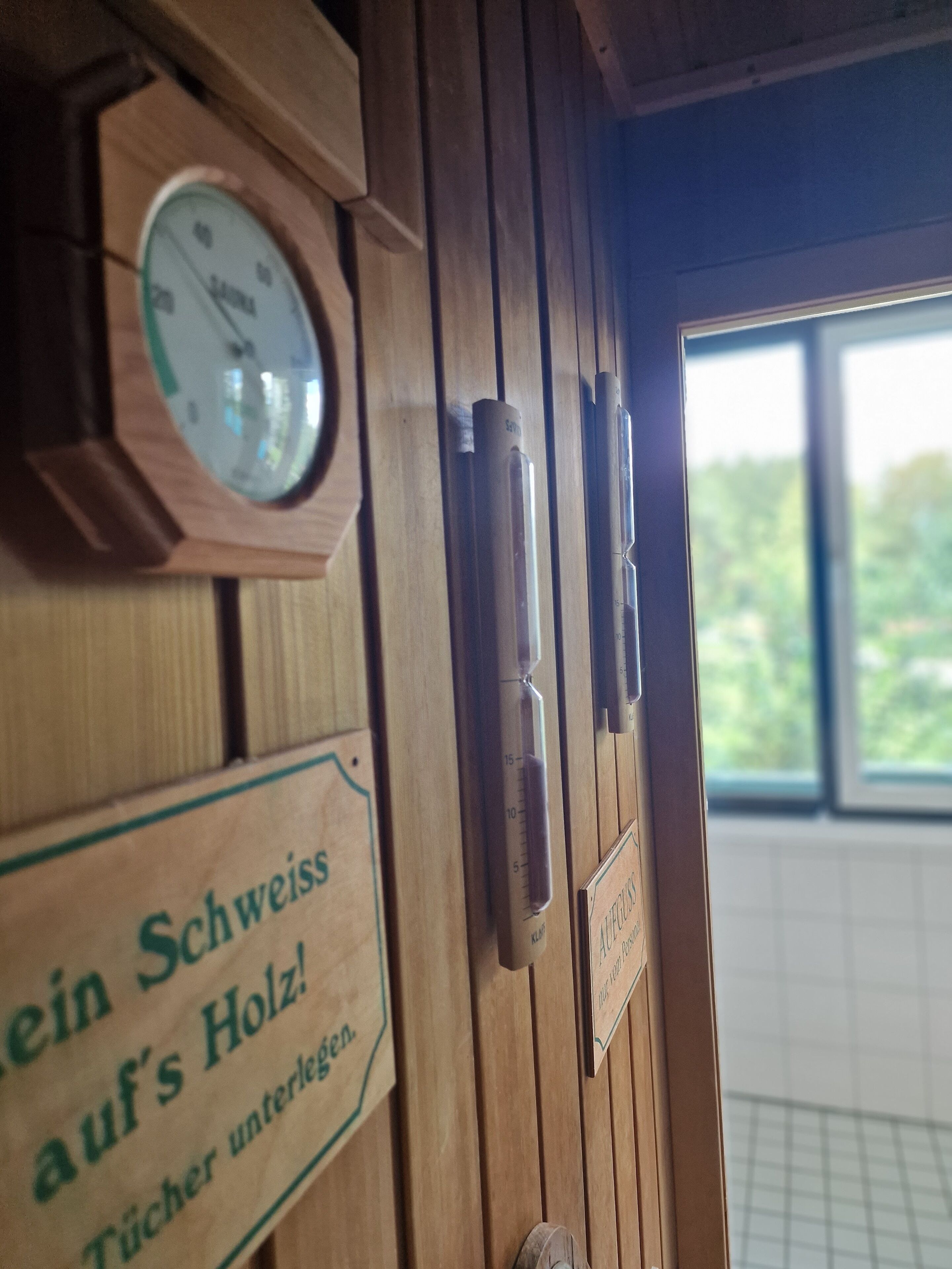 A wooden door with a clock and signs in German.