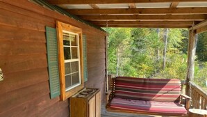 A wooden cabin with a porch, a bench, and a window with shutters. - Charming Cabin near Kentucky LK (Camden)