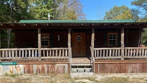 A rustic cabin with a green roof, wooden porch, and a small front door. - Charming Cabin near Kentucky LK (Camden)