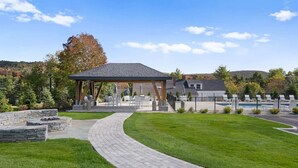 A covered patio with outdoor furniture, a stone fire pit, and a well-maintained lawn. - The Trailside Retreat | Ski on&off w/ Fireplace! (Dover)