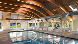An indoor swimming pool with a wooden ceiling, clear glass windows, and white lounge chairs. - The Trailside Retreat | Ski on&off w/ Fireplace! (Dover)