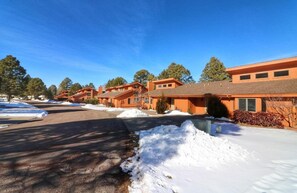 A row of modern, two-story buildings with a uniform orange facade, a paved driveway, and snow on the ground. - 2Bed/2Bath Deluxe Suite in Flagstaff! Complete w/Golf, Pools, and More! (Flagstaff)